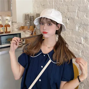 Detail shot of a Japanese style white ruffled bucket hat worn by a model in a cozy cafe