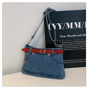Detailed view of trendy denim crossbody bag featuring unique jean waist design and red belt