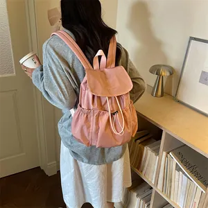 Back view of a woman wearing a pink drawstring pleated backpack in a lifestyle setting