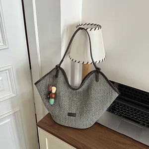 Large capacity woven straw beach tote bag with colorful charm on a wooden desk