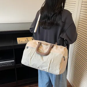 Stylish cream and white travel duffel bag shown on a shoulder for scale