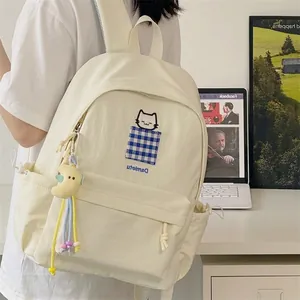 Cream-white student backpack featuring cat embroidery and moon keychain lifestyle view