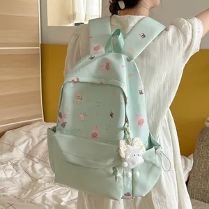 Close-up of a sweet mint green backpack with cute animal prints and a plush charm