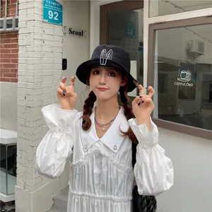 Detail view of a cute black bucket hat with white rabbit ears embroidery worn by a model