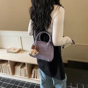 Commuter purple Boston bag with cute bear charm shown on a female model's shoulder
