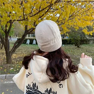 Back view of a beige plush landlord hat for women in an autumn park lifestyle setting