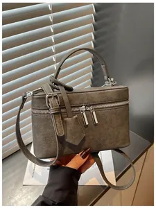 Detailed view of gray box-shaped vanity handbag with top handle and double silver zippers