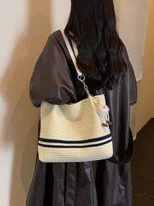 Stylish woven tote bag with navy blue stripes and white furry charm for summer