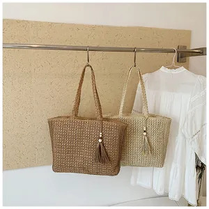 Vue détaillée de deux sacs cabas en paille tressée beige et marron suspendus sur un support.