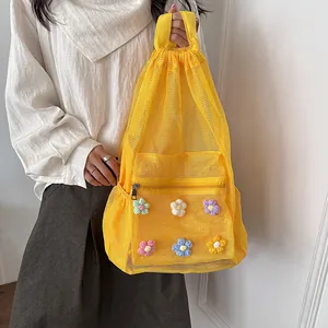Close-up detail view of a vibrant yellow mesh backpack featuring colorful knitted flower accents