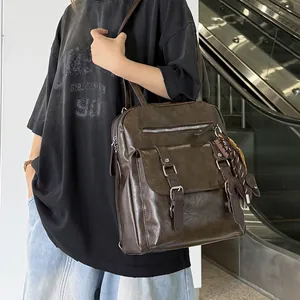 Large brown faux-leather commuter backpack shown on a model in a modern urban setting.