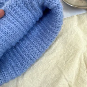 Detailed macro view of a light blue chunky knit beanie hat showing soft wool yarn texture