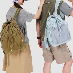 Detail view of stylish grid pattern drawstring backpacks with mesh pockets worn by models.