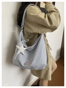 Model met een grote blauw geruite draagtas met een sterbedeltje en een patch