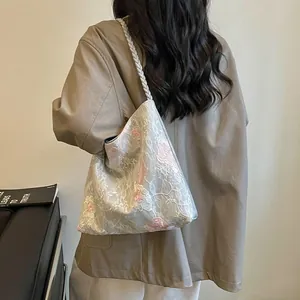 Detailed back view of a woman carrying a floral embroidered shoulder bucket bag with braided strap