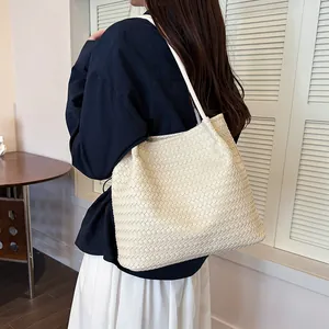 Back view of a person carrying a large cream white vintage woven tote bag in a room