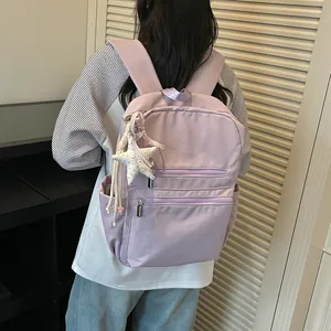 Vista trasera de una mochila lavanda ligera con colgante de estrella en una modelo