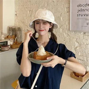 Detail shot of a white wavy brim bucket hat worn by a model in a cafe setting