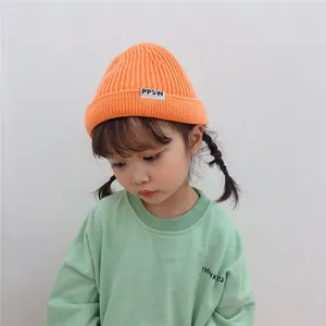 Close-up of a young child wearing an orange ribbed knitted beanie with PPSW tag