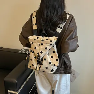 Detailed rear view of a cream polka dot backpack worn by a model in casual wear