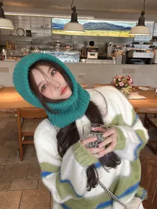 Stylish Asian woman in a cafe wearing a turquoise knitted balaclava neck warmer hat