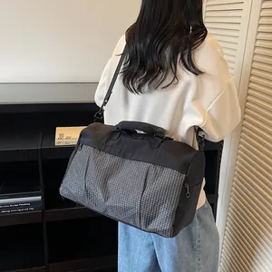 Detailed view of a stylish black and grey grid travel bag being carried by a person