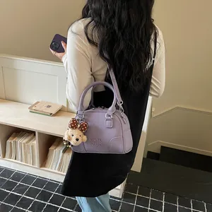 Elegant purple Boston commuter handbag with cute plush bear charm carried on shoulder