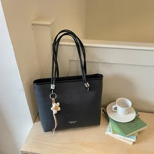 Elegant black large capacity tote bag with a floral charm in a cozy lifestyle setting