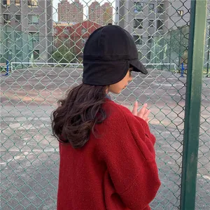 Side view of a black women's trapper hat with ear flaps for winter warmth