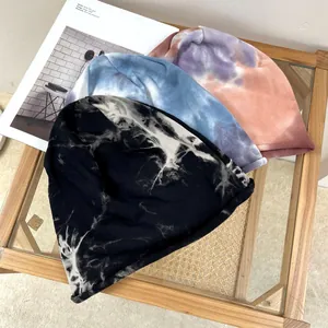 Close-up detail showing three different stylish tie-dye patterns on soft cotton beanies