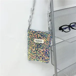 Dettaglio di una borsa a tracolla per cellulare con paillettes appesa a uno scaffale metallico