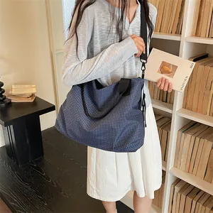 Borsa da viaggio capiente a scacchi blu mostrata in un ambiente di biblioteca