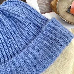 Detailed macro view of light blue chunky knit beanie showing ribbed wool texture