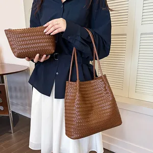 Detailed view of brown retro woven tote bag and matching pouch held by a model.