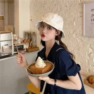 Elegant white ruffled bucket hat for women shown in a lifestyle cafe setting.