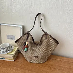 Detail of handmade woven straw tote bag with brown leather strap and colorful beads