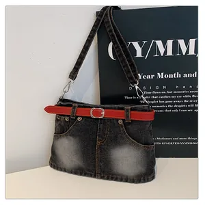 Close-up detail of a dark washed denim shoulder bag featuring a unique red belt accent