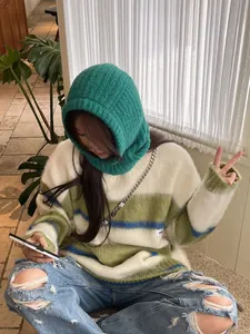Stylish young woman wearing a green knitted balaclava hooded scarf for cozy winter warmth