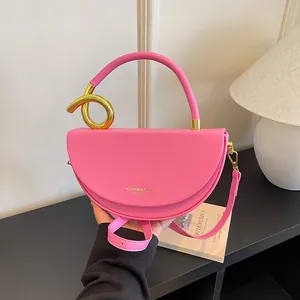 Stilvolle pinkfarbene Satteltasche mit einem dekorativen goldenen Knotengriff am Henkel.