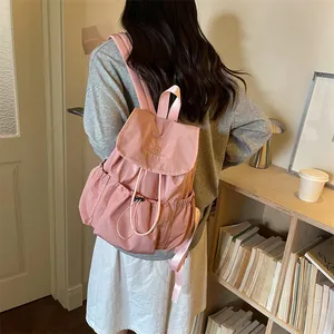 Back view of a girl wearing a stylish pink drawstring ruched backpack in a cozy library