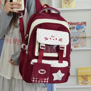 Detalle de una linda mochila escolar granate con solapa de orejas de gato y bolsillos