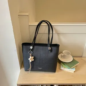 Detailed view of a black large capacity tote bag with a decorative flower charm