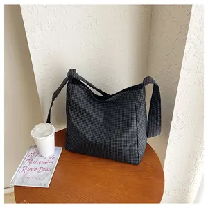 Large capacity checkered nylon shoulder bag displayed on a wooden table with a coffee cup