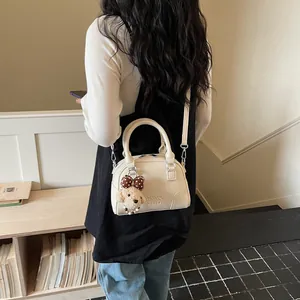 White Boston handbag with poodle charm detail, high-end commuter crossbody pillow bag.