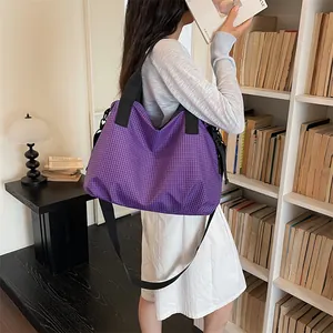 Modella che indossa una borsa da viaggio a scacchi viola in una biblioteca per lo stile