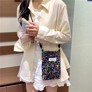 Dettaglio di una mini borsa per cellulare a paillettes colorate indossata da un modello