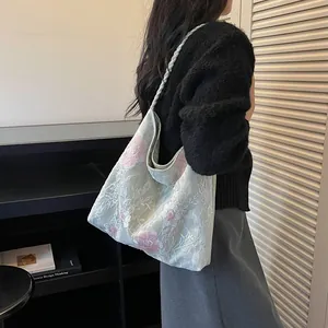 Detailed view of the floral embroidered bucket bag worn on the shoulder by a model.
