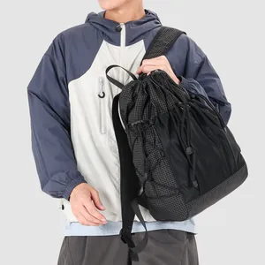 Detailed view of a fashionable black grid drawstring backpack being carried by a model