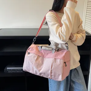 Pink travel duffel bag shown on shoulder of model for stylish outdoor sports use