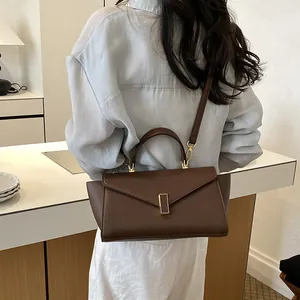 Back view of model carrying a classic brown leather handbag with gold buckle detail.